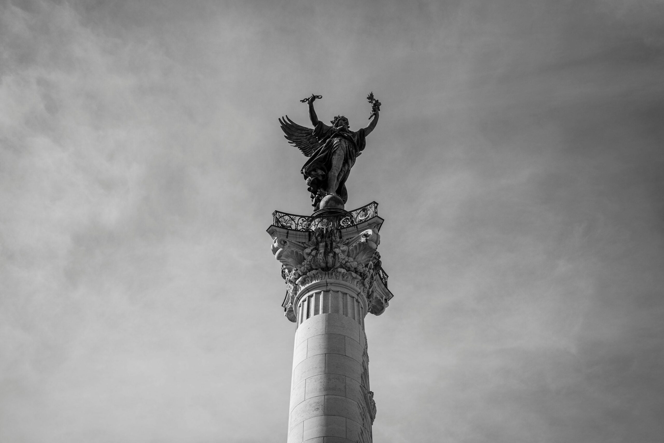 Black and white photo of a monumental column and statue in Bordeaux, France.